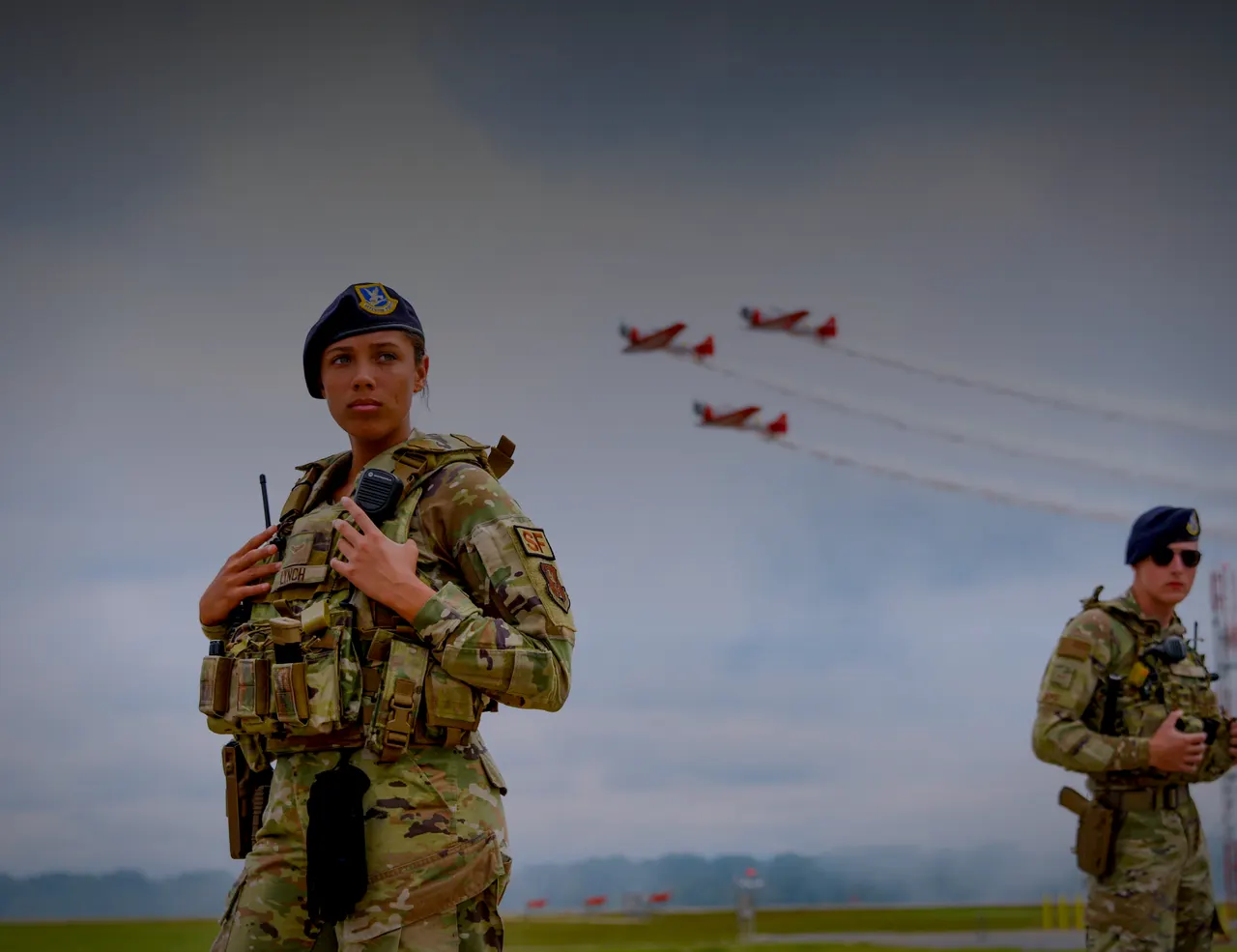 U.S. Air Force security forces airman on a flight line in a plate carrier, aircraft passing overhead